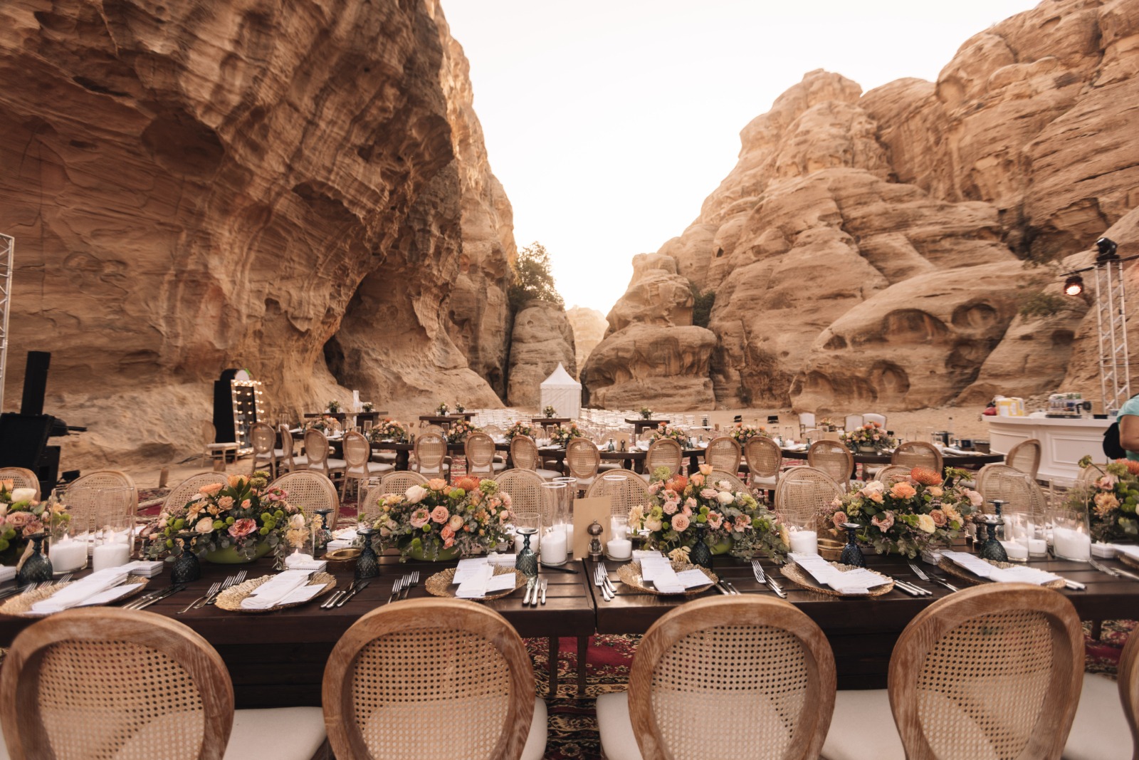 Long banquet tables with floral centrepieces between sandstone cliffs, Mövenpick Resort Petra