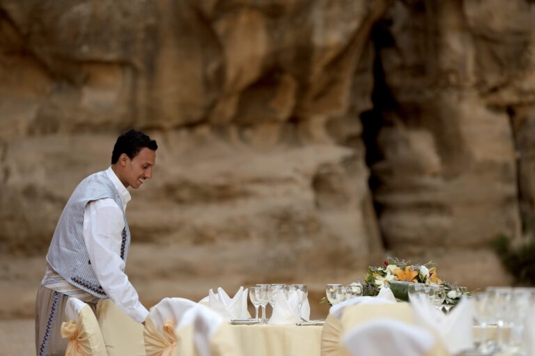 Staff setting a banquet table against a sandstone wall at Little Petra, Mövenpick Resort Petra