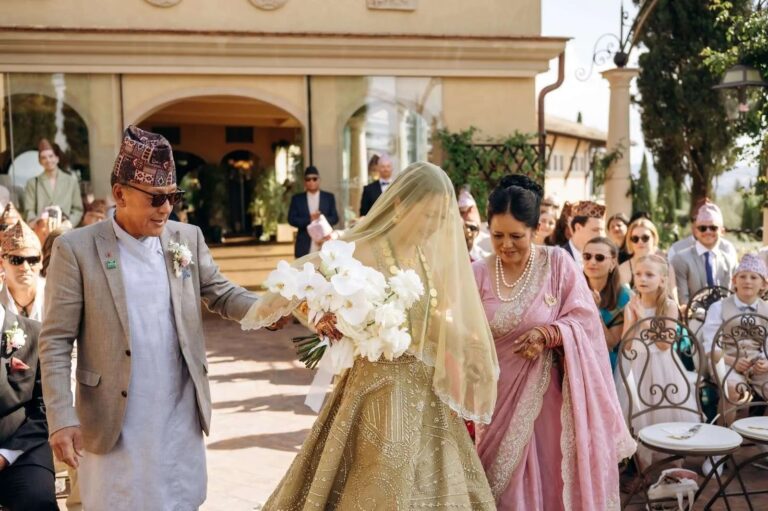 Led in under a gold veil with white orchids, guests in saris and topi caps, Magnolia Wedding Planner