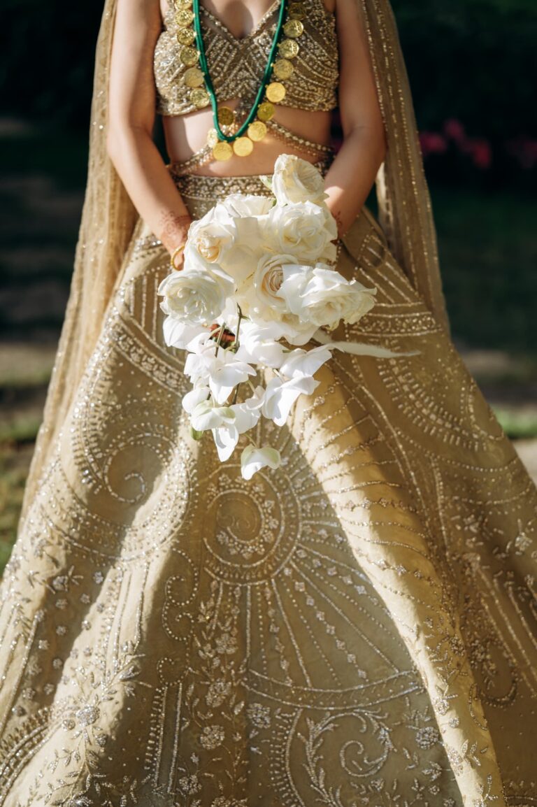Gold embroidery on a lehenga with a bouquet of white orchids, Magnolia Wedding Planner