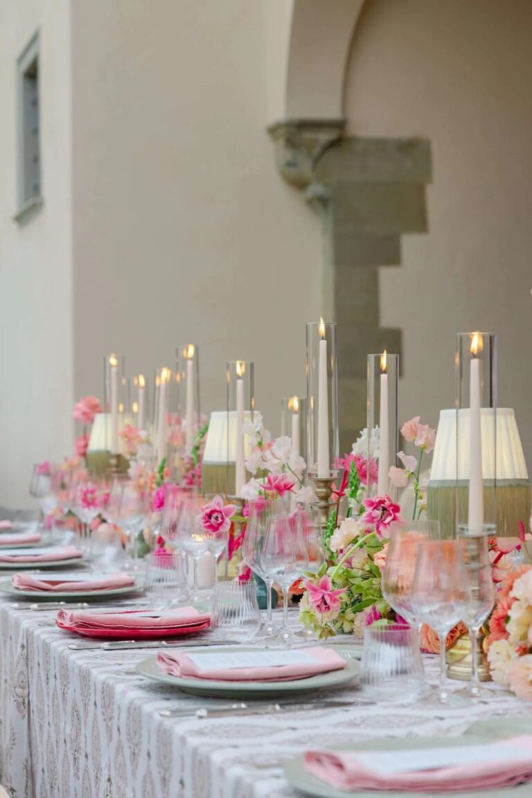A table under a line of tall candles, magenta and coral flowers down the cloth, Magnolia Wedding Planner