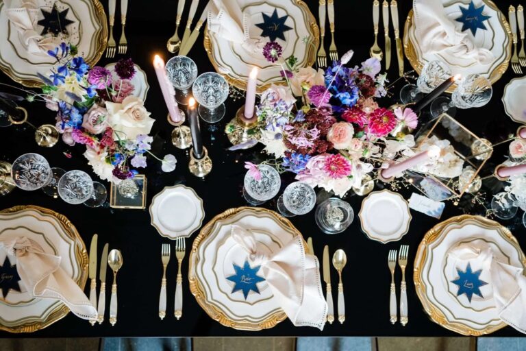 A black cloth laid with star-patterned porcelain, dark dahlias and taper candles, Magnolia Wedding Planner
