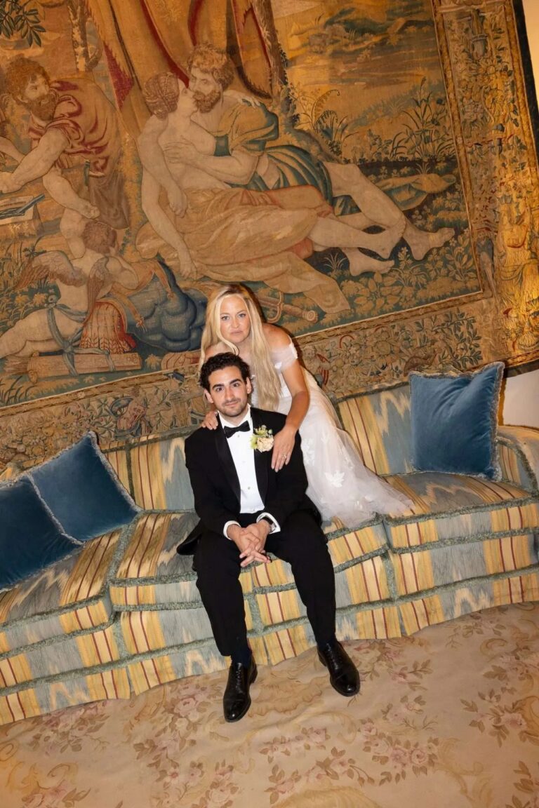 The couple on a striped sofa beneath a Renaissance tapestry, Magnolia Wedding Planner