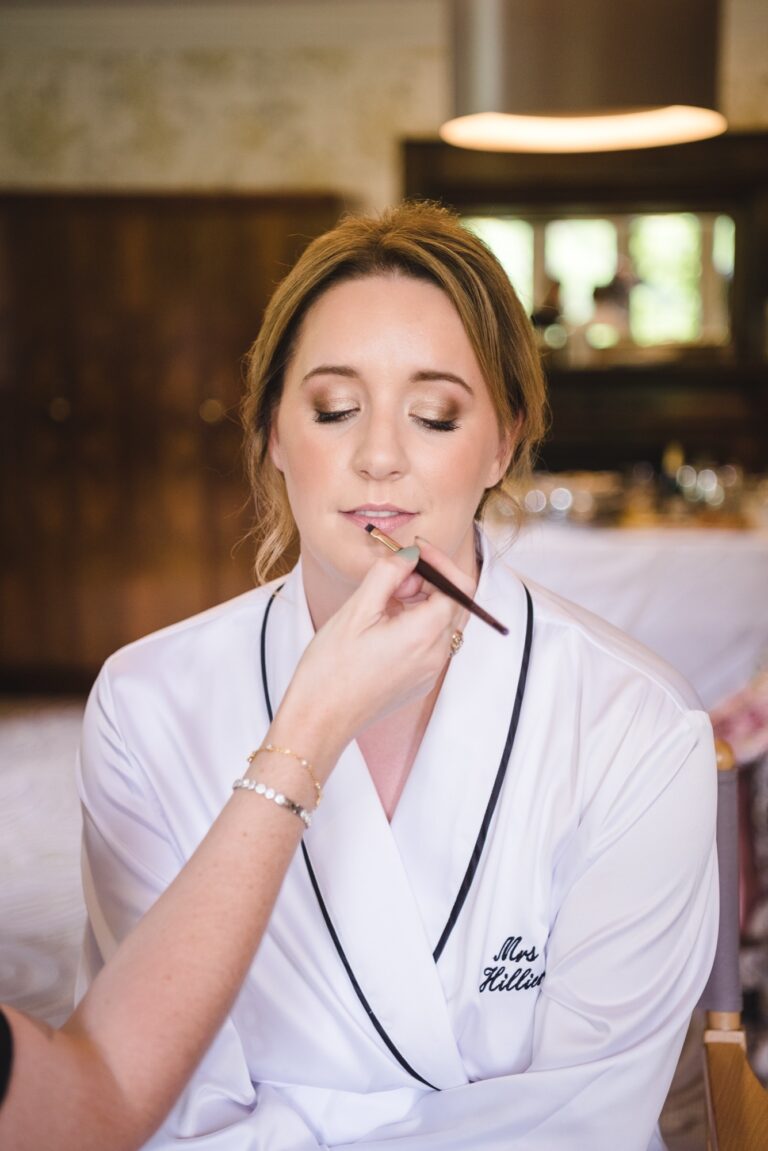A close self-portrait, applying lipstick in a mirror, a monogrammed white robe, Makeup By Becky Flynn