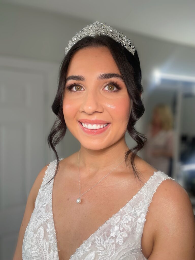 A bride in a beaded lace gown and pearl tiara, a wide smile, Makeup By Becky Flynn