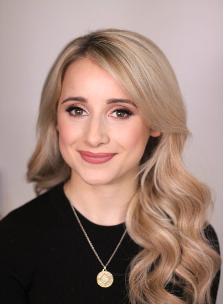 A woman in a black top, a layered gold necklace, soft waves, Makeup By Becky Flynn