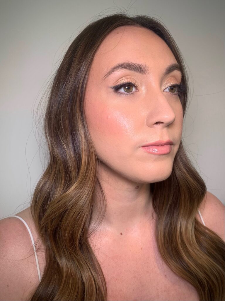 A woman in profile, long wavy hair, a gold drop earring, Makeup By Becky Flynn