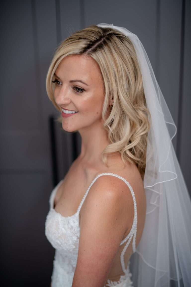 A bride in profile, loose waves, a veil and drop earrings, Makeup By Becky Flynn