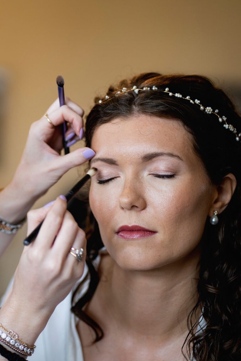 Eyeshadow being applied to a bride wearing a pearl headband, eyes closed, Makeup By Becky Flynn