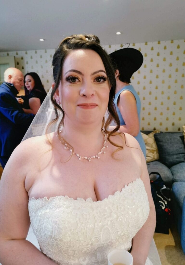 A bride's portrait, veil and pearl necklace, guests behind her, Makeup By Mirna