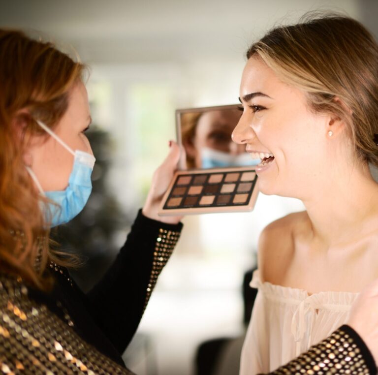 Mirna at work, mid-application, a client mid-laugh, Makeup By Mirna