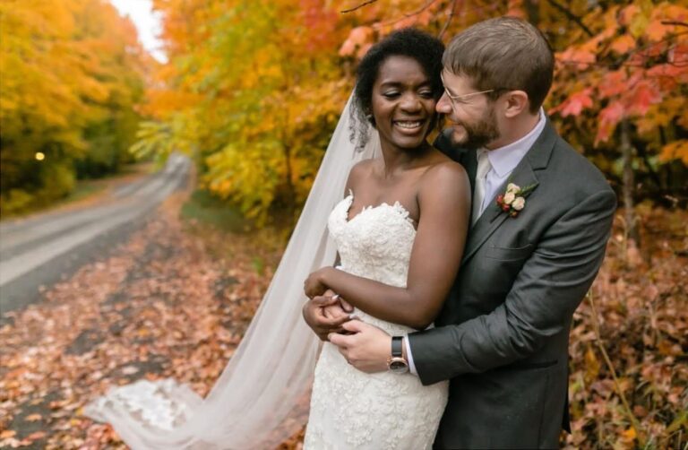 A couple embracing on a country lane covered in fall leaves, Maple Leaf Weddings