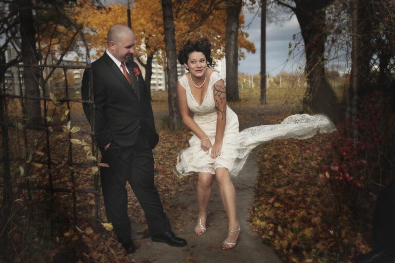 A bride and groom in a fall garden, the bride's veil lifted by the wind, Maple Leaf Weddings