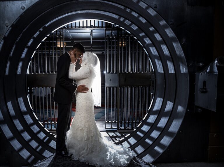 A couple embracing in the open round door of a bank vault, King West, Toronto, Maple Leaf Weddings