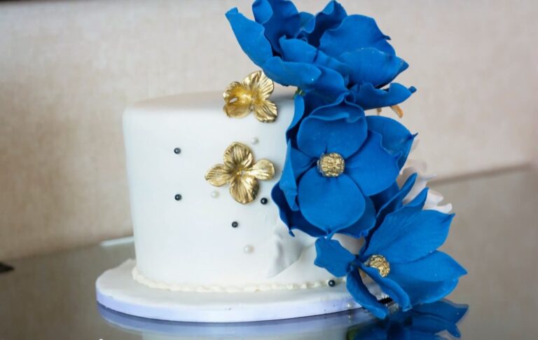 A white wedding cake with blue and gold sugar flowers, Maple Leaf Weddings