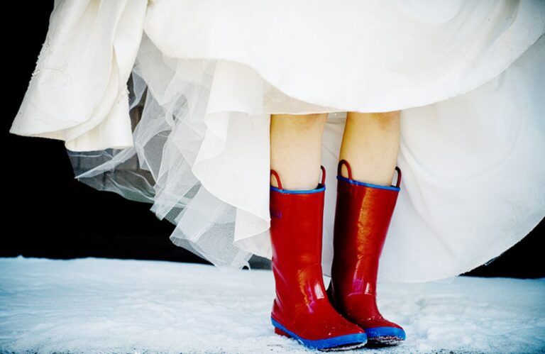 A bride's red rain boots in the snow beneath a tulle skirt, Maple Leaf Weddings