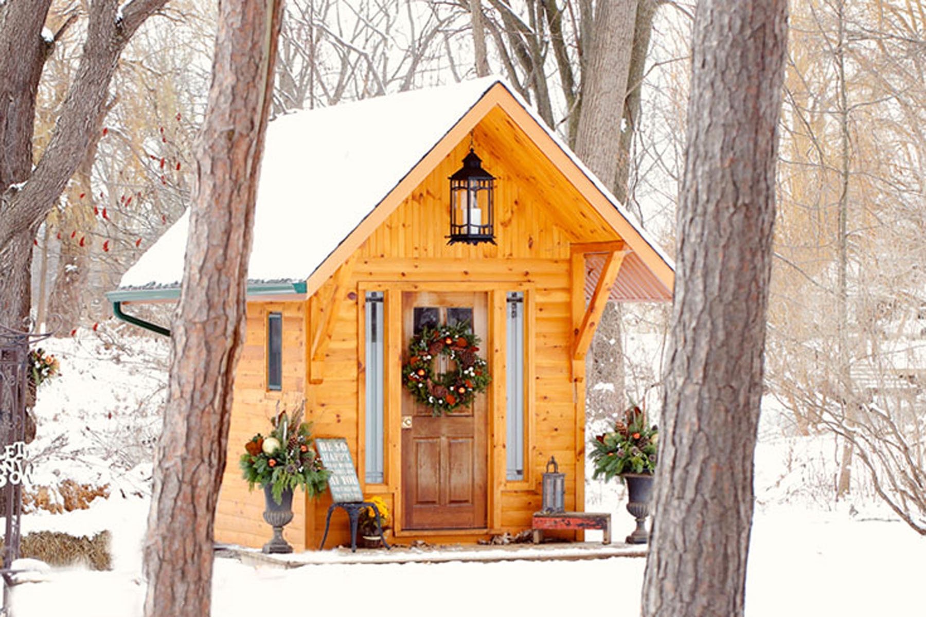The Little Log Chapel dressed with a wreath and lanterns among snow-covered trees, Niagara, Maple Leaf Weddings