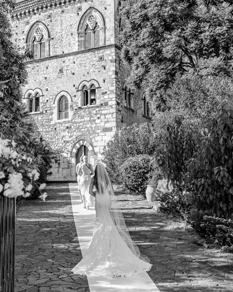 The bride walking toward a medieval palazzo garden in Taormina, Marco Ficili