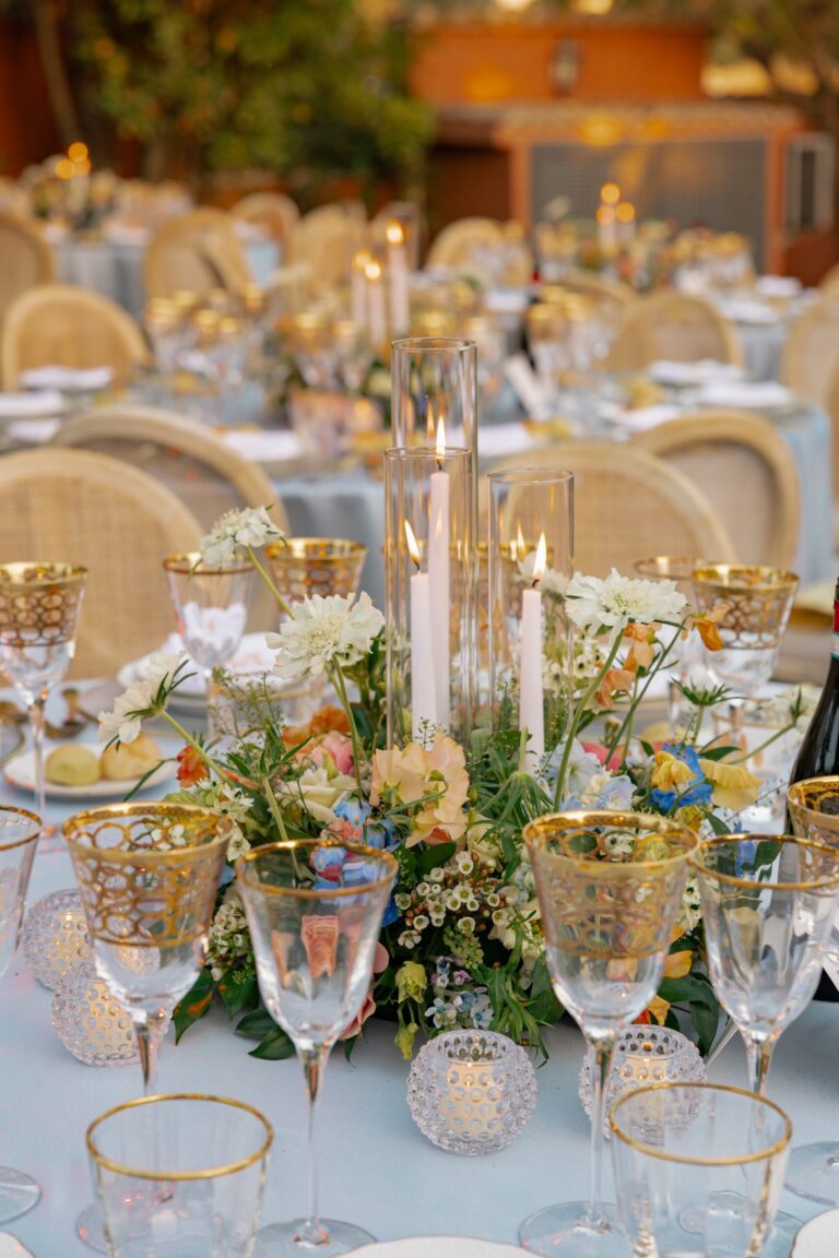 A table centrepiece beneath tall glass hurricane candles, Maria Luisa Rocchi Flowers