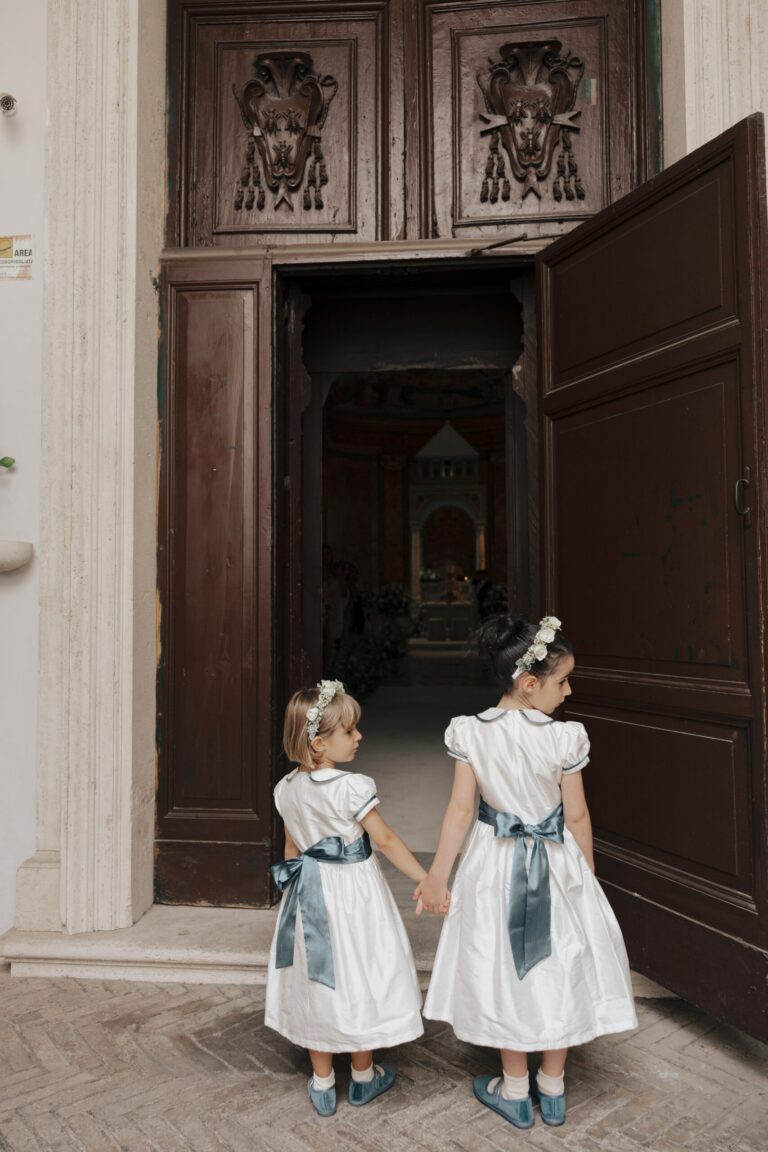 Two flower girls, hand in hand, at the church door, Maria Luisa Rocchi Flowers