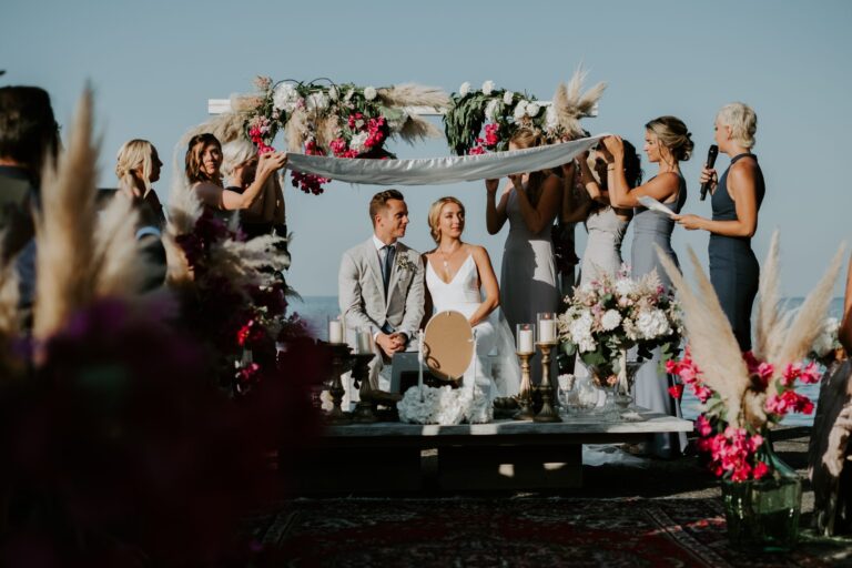 A ceremony under a floral canopy held up by the wedding party, pampas either side, Marica Events