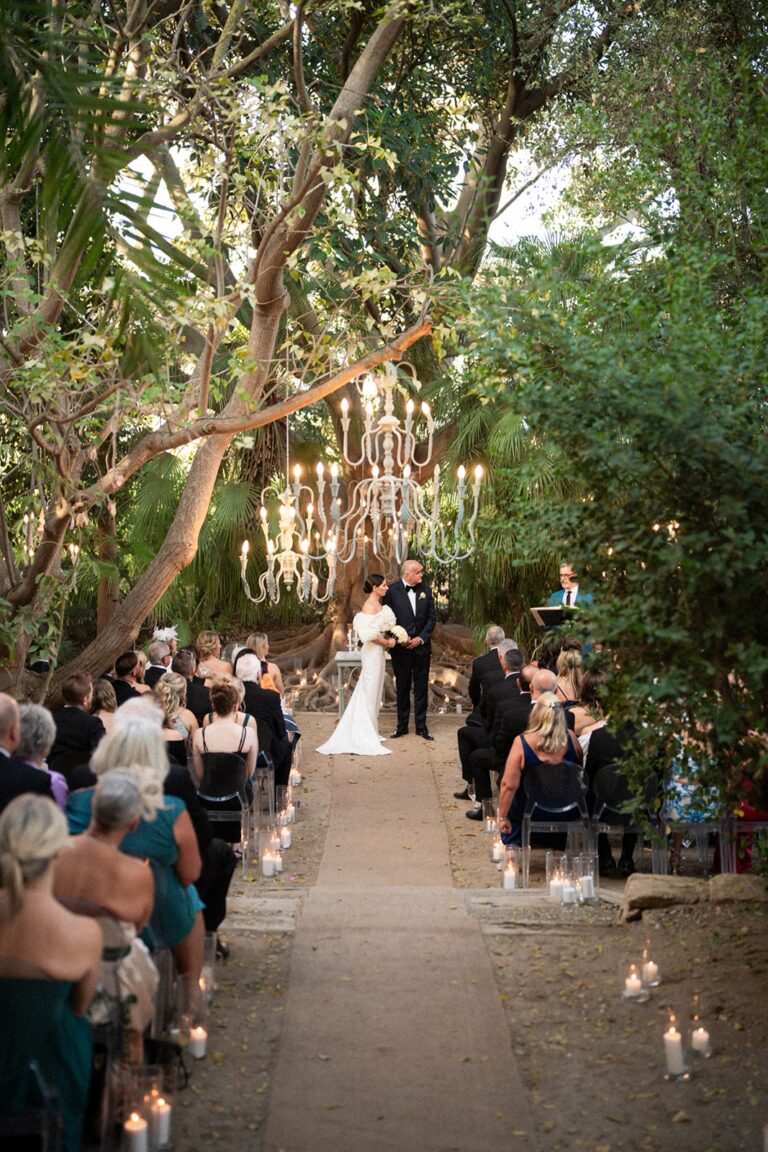 The aisle under old trees, crystal chandeliers hung in the branches, candles along it, Marica Events