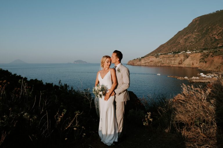 The couple on a dark hillside at dusk, a headland to one side, islands on the horizon, Marica Events