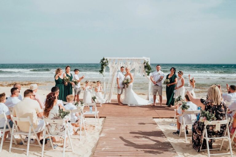Beach ceremony on a timber deck with guests under a white arch, Paphos, Marry Me Cyprus
