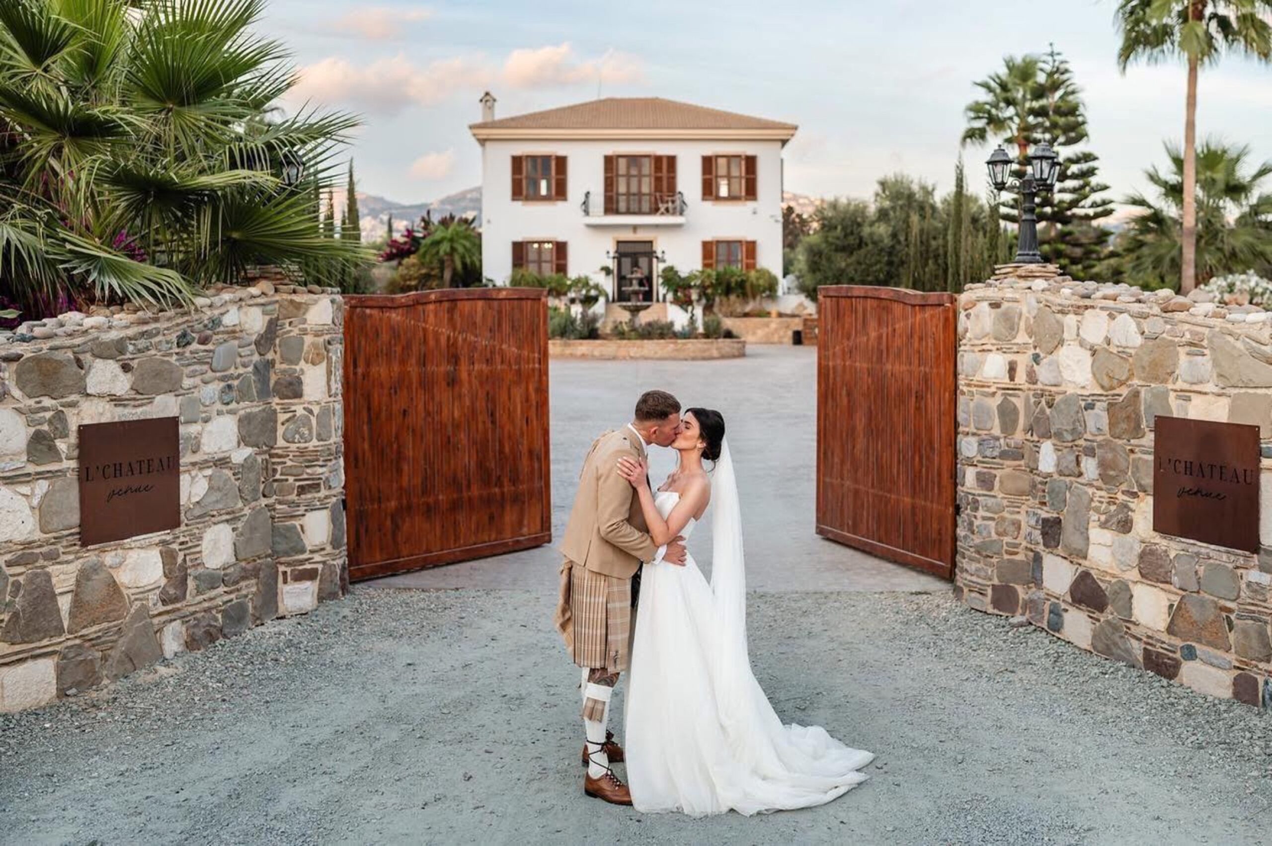 Couple kissing between the stone gate posts at L'Chateau, Tala, Paphos, Marry Me Cyprus