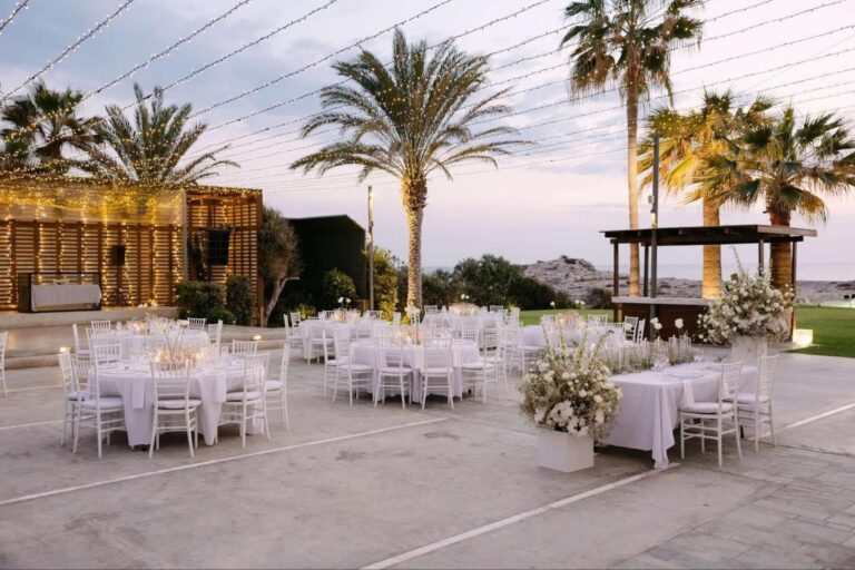 Round-table reception under palm trees with festoon lights at Alassos, Paphos, Marry Me Cyprus