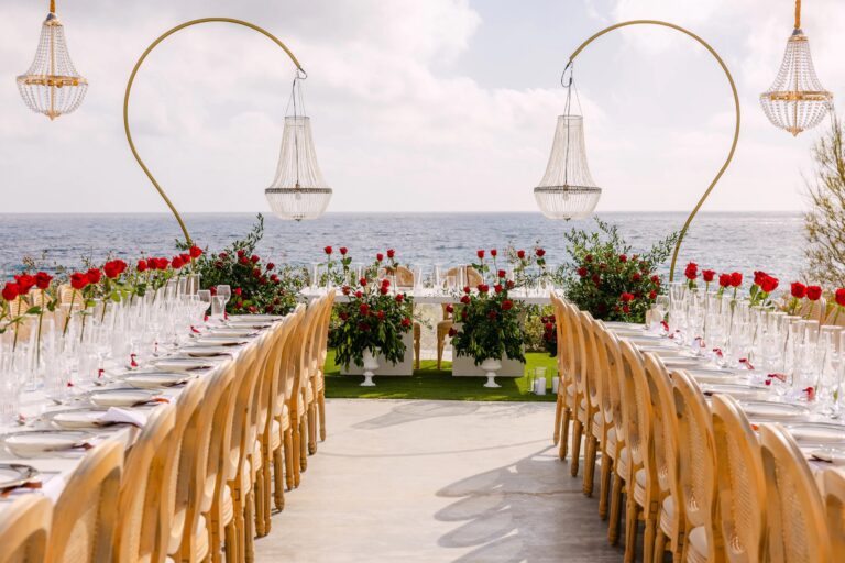 Long reception tables with gold arches, chandeliers and red roses at OZEA, Sea Caves, Paphos, Marry Me Cyprus