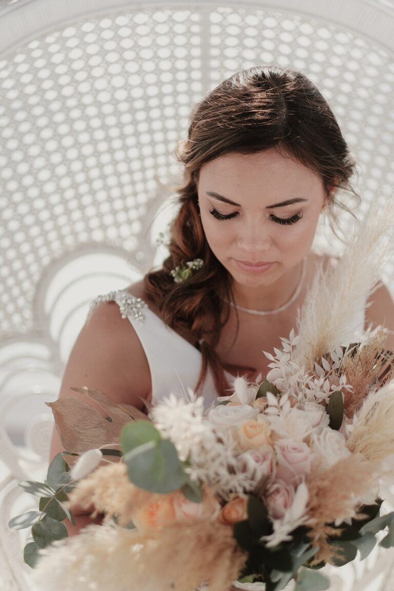 Bride looking down at a blush and cream bouquet, Marryme in Greece