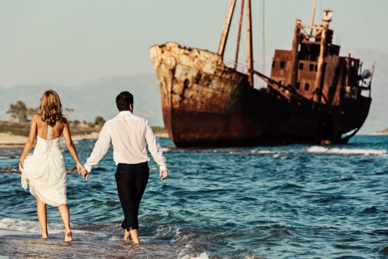 Couple walking in the shallows beside a rusted shipwreck, Marryme in Greece