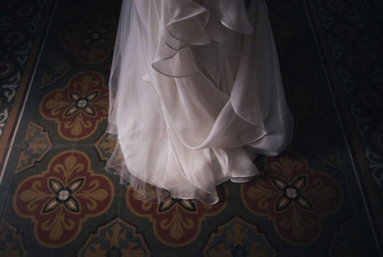 The hem of a wedding dress on a patterned tile floor, Masseria Spina Resort