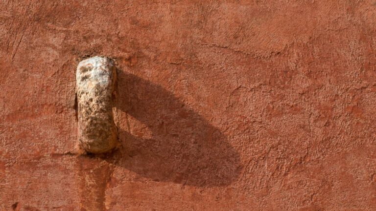 A stone detail on a red wall of the masseria, Masseria Spina Resort