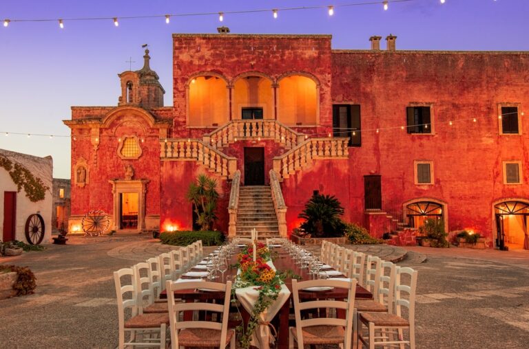 The main square of the masseria at dusk with a long table laid, Masseria Spina Resort