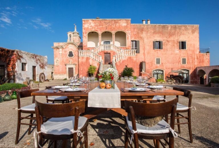 A table laid in the main courtyard in front of the red-walled masseria, Masseria Spina Resort
