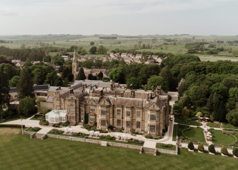 Aerial view of the hall and its formal gardens, with Matfen village and the church spire behind, Matfen Hall