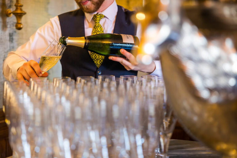 Champagne being poured into rows of glasses for a reception, Matfen Hall