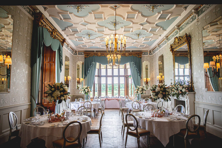 The Drawing Room set with round tables and tall flower arrangements, under its ornate painted ceiling, Matfen Hall