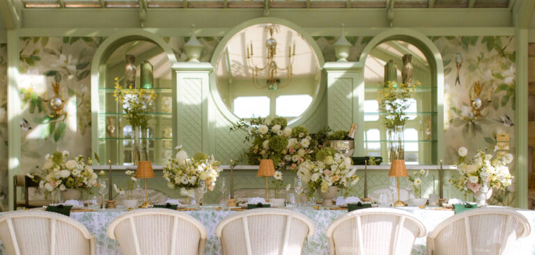 A long top table dressed with white and green flowers in front of trellised panels and arched mirrors, Matfen Hall