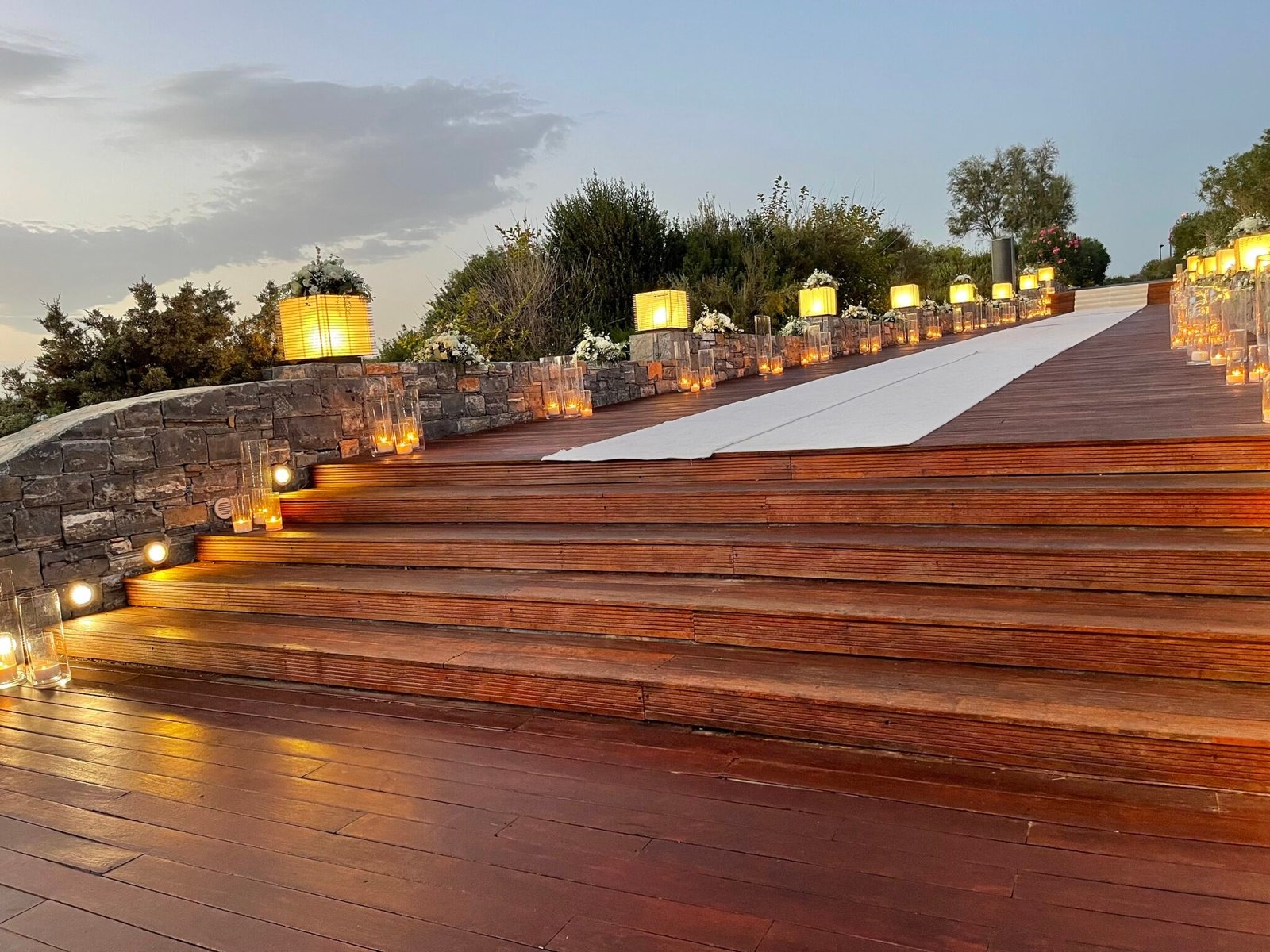 Wooden steps lit by lanterns, with a white aisle runner, Mathioudakis Exclusive Events