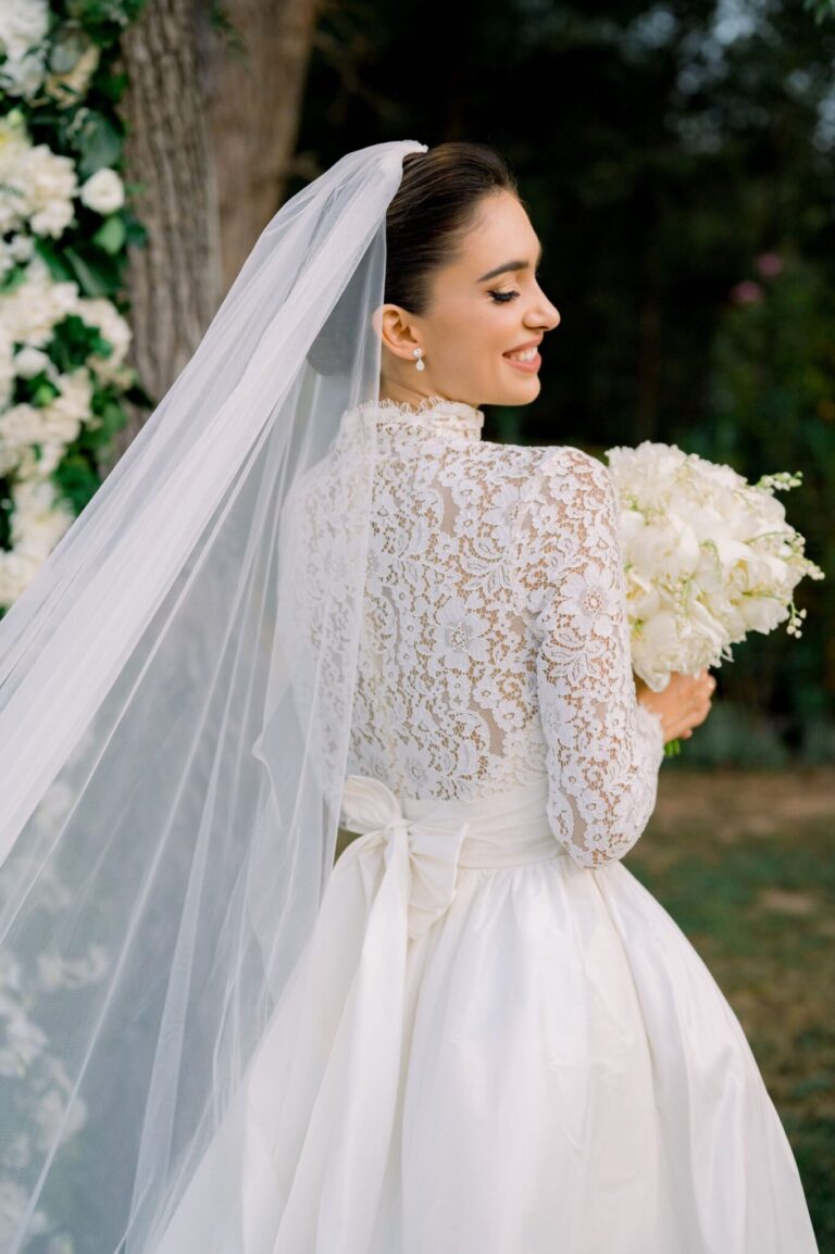 Bride in a lace gown and veil holding a white bouquet, Mathioudakis Exclusive Events