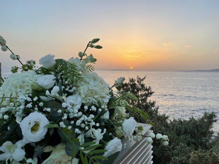 White flowers in the foreground with the sea at sunset, Mathioudakis Exclusive Events