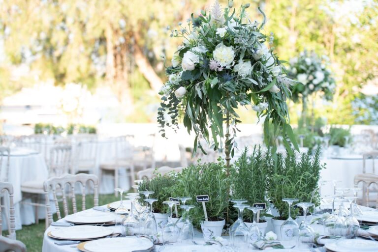 Table with a white floral arrangement and herb planters, Mathioudakis Exclusive Events