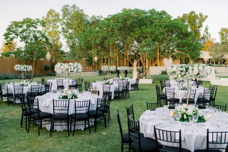 Round tables with tall white floral centrepieces on a lawn, Mathioudakis Exclusive Events