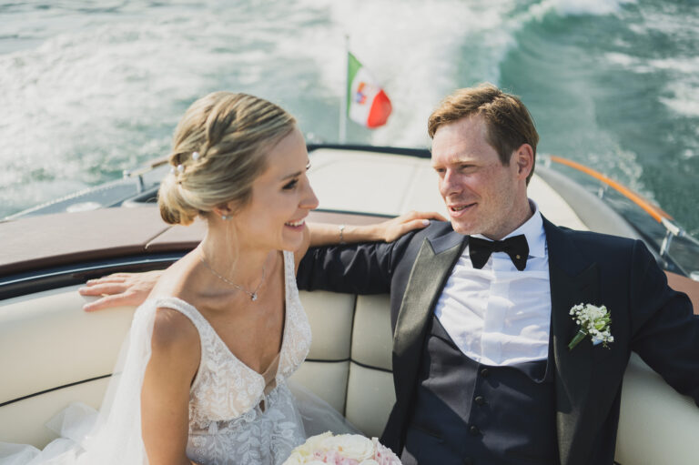 A newly married couple on a wooden motorboat on Lake Como, the Italian flag at the stern, Matteo Cuzzola Photography