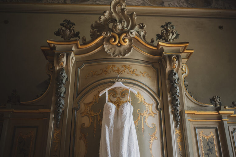 The wedding dress hanging against a gilded, carved doorway, from his Villa Erba page, Matteo Cuzzola Photography