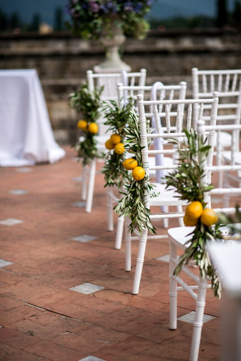 White chairs dressed with lemons and greenery for a ceremony at Castello di Vincigliata, near Florence, Matteo Cuzzola Photography
