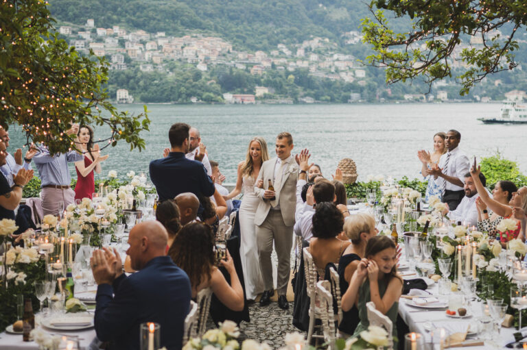 Guests on their feet applauding the couple at a lakeside dinner, Villa Regina Teodolinda, Matteo Cuzzola Photography